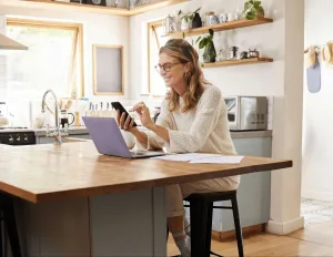 A woman looking at her smart phone and laptop